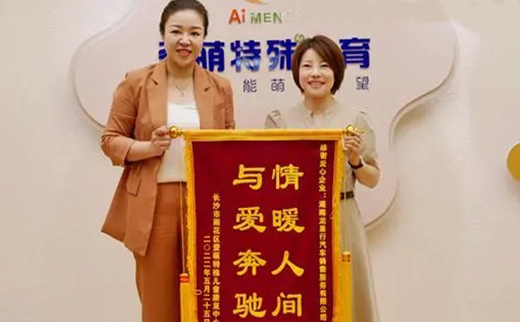 长沙爱萌特殊儿童中心的郑校长（右一）向湖南龙星行奔驰总经理张玲颁发锦旗