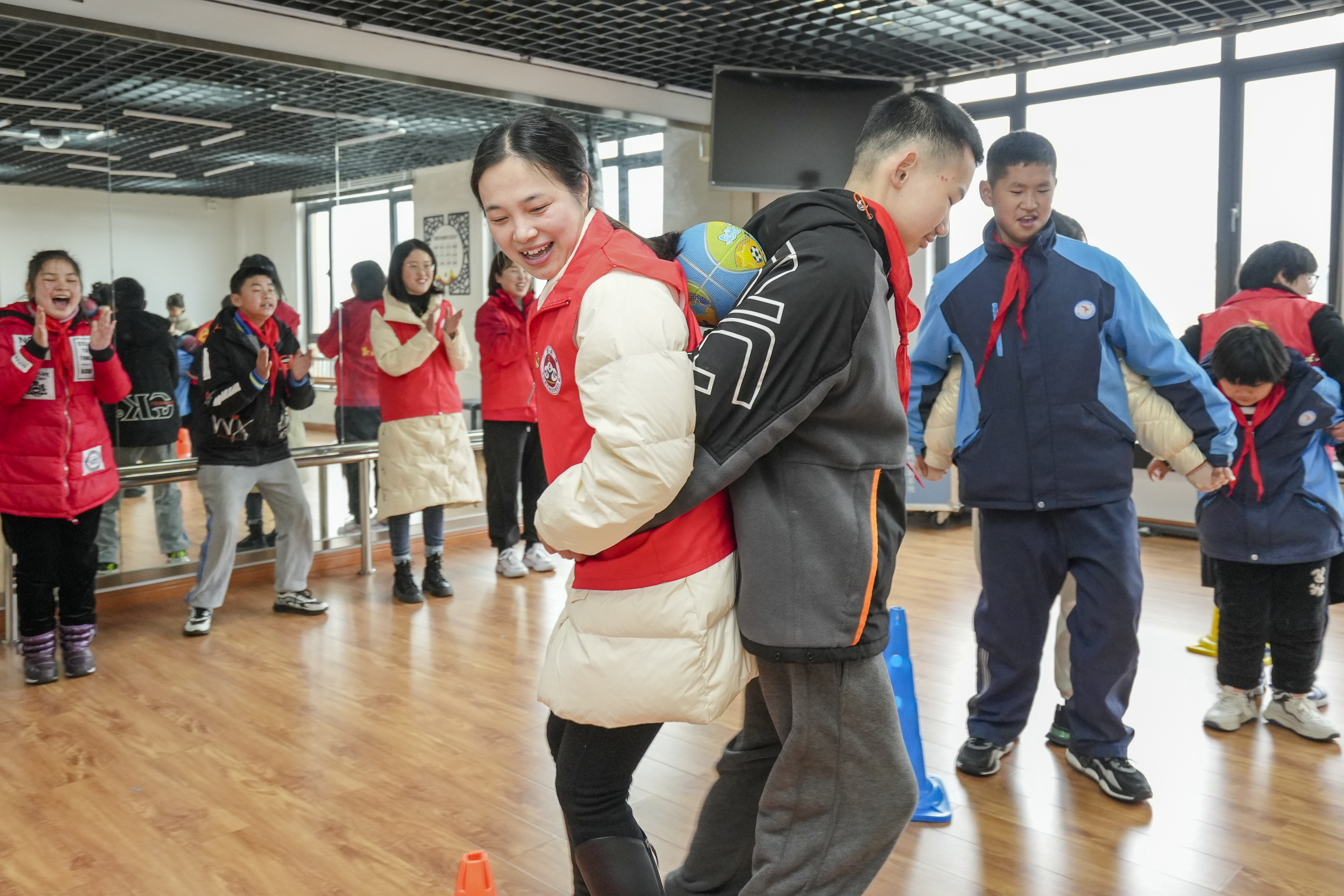 浙江省湖州市长兴县培智学校内，孩子们和党员教师一起进行“皮球接力”游戏。