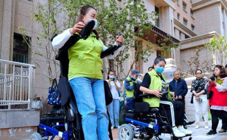 图为工作人员演示站立轮椅租赁使用方法